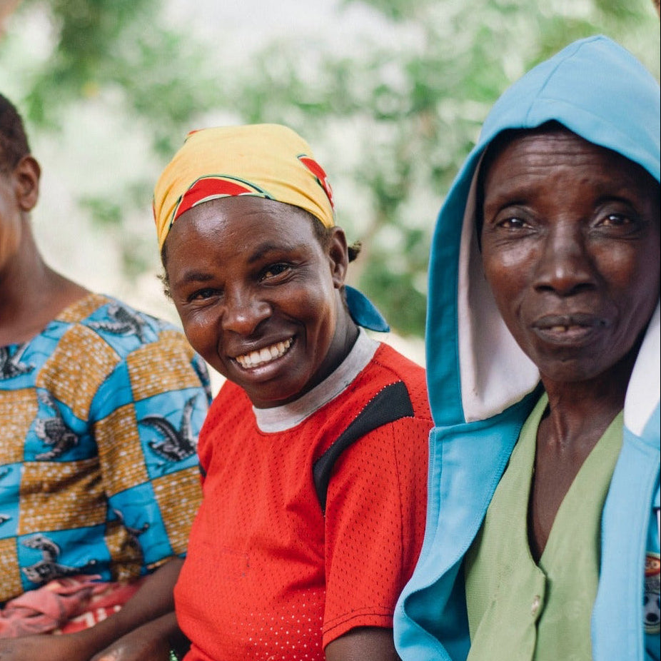 Three women sitting together with a basket, surrounded by nature, with text about corporate gifts and contact information.
